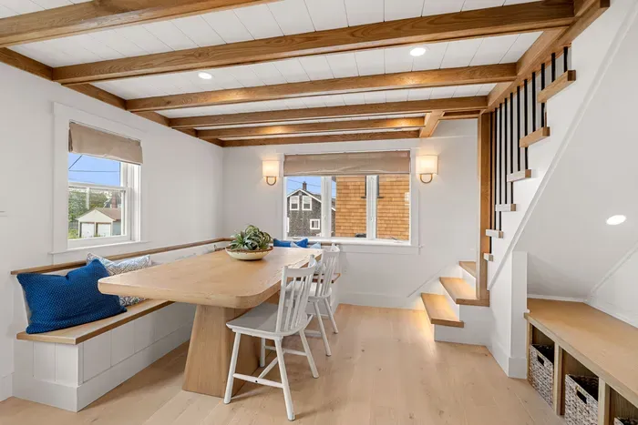 Bright dining nook with built-in seating, wood beams, and coastal charm