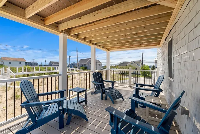Spacious covered porch with Adirondack seating and water-view glimpses