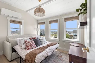 Bright guest room with sleeper sofa, natural light, and water views