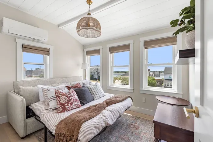 Bright guest room with sleeper sofa, natural light, and water views