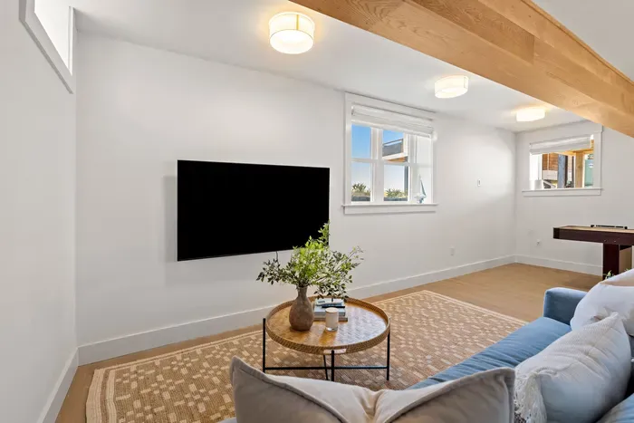 Bright modern lounge with TV, cozy seating, and bonus game space