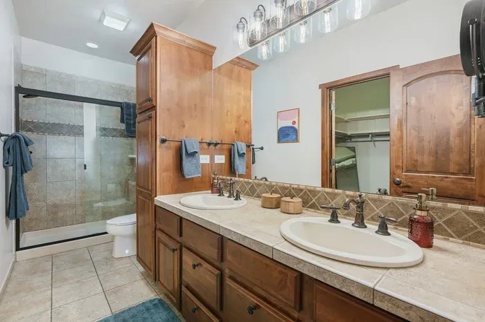 Primary bathroom with walk-in glass shower and double sinks.  Adjacent walk-in closet with full-length mirror and a luggage rack. 

The walk-in closet is a great sleeping place for little ones in the pack-n-play. :)