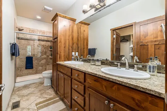 Primary bathroom with double vanity and attached walk in closet.