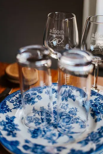 Elegant table setting featuring blue-and-white floral china, wine glasses, and polished glassware, creating a refined and inviting dining experience.