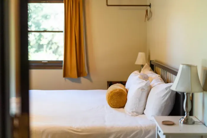 Cozy bedroom with crisp linens, soft bedside lighting, and warm natural light from the window.