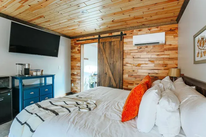Cozy suite bedroom with a comfortable bed, rustic wood accents, smart TV, and convenient in-room amenities.