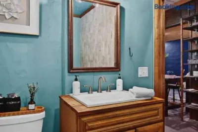 Charming bathroom vanity with a turquoise textured wall, warm wood cabinetry, framed mirror, polished faucet, neatly folded towel, and simple guest amenities.