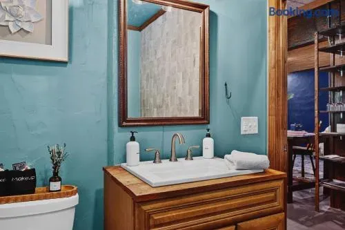 Charming bathroom vanity with a turquoise textured wall, warm wood cabinetry, framed mirror, polished faucet, neatly folded towel, and simple guest amenities.
