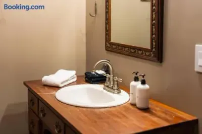 Cozy bathroom vanity featuring a warm wooden countertop, vintage-style framed mirror, polished chrome faucet, neatly folded towels, and simple toiletry bottles.