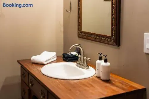Cozy bathroom vanity featuring a warm wooden countertop, vintage-style framed mirror, polished chrome faucet, neatly folded towels, and simple toiletry bottles.