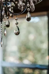 Elegant crystal chandelier details catching the light against a scenic forest backdrop.