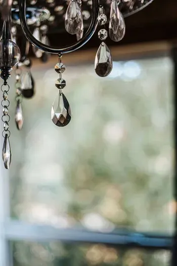 Elegant crystal chandelier details catching the light against a scenic forest backdrop.