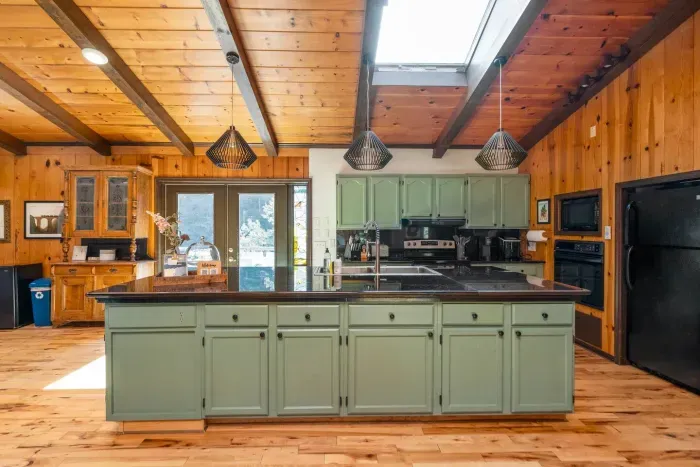 Fully Equipped Kitchen: Spacious kitchen with a large island, modern appliances, ample counter space, and warm cabin-style wood accents.