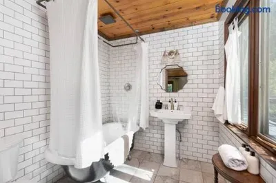 Charming Claw-Foot Tub Bathroom — Bright and inviting bathroom featuring a classic claw-foot tub with shower, crisp white subway tiles, a pedestal sink, and plenty of natural light.
