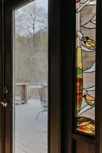 Scenic Deck Access: Step outside onto the private deck and enjoy peaceful wooded views through the elegant stained-glass doorway.