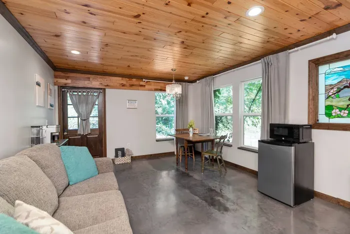 Bright, inviting living space with cozy seating, a dining nook, and large windows overlooking the greenery.