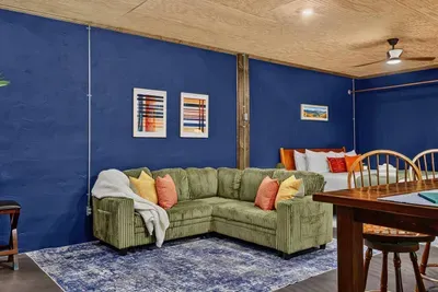 Cozy Garden Suite living area with a comfortable sectional sofa, dining space, and a bedroom area in the background.