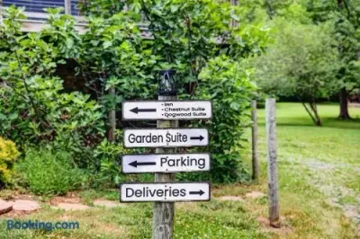 Garden property wayfinding sign surrounded by lush greenery, clearly directing guests toward the Inn, Chestnut Suite, Dogwood Suite, Garden Suite, parking, and deliveries.