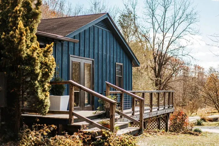 **Charming Cabin Retreat:** Beautiful blue cabin with a spacious deck, surrounded by peaceful wooded scenery—perfect for enjoying the outdoors.