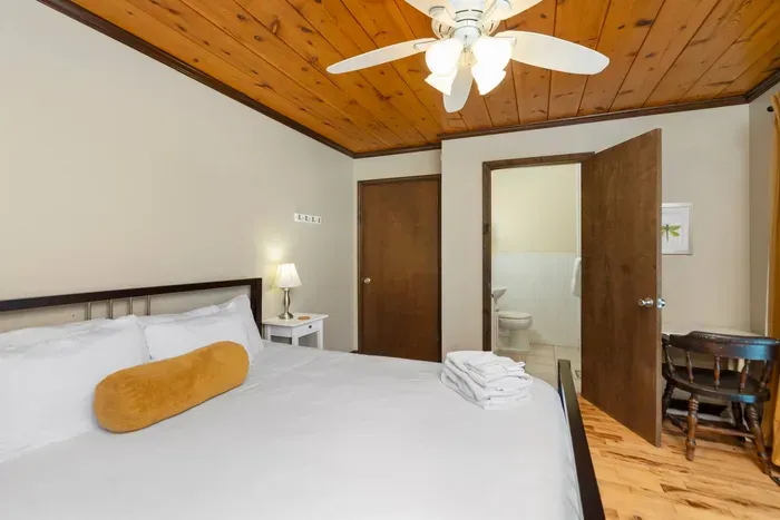 Comfortable Bedroom: Cozy bedroom with a comfortable bed, fresh linens, warm wood accents, ceiling fan, and convenient access to the bathroom.