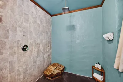 Walk-in shower with a rainfall showerhead, stone tile accents, and a modern rustic design.
