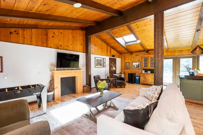 Rustic Great Room: Spacious open-concept living area with a cozy fireplace, foosball table, comfortable seating, and warm wood accents.