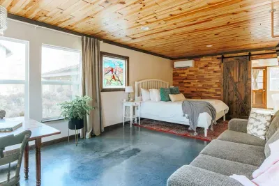 Bright, spacious suite with a comfortable queen bed, cozy sofa, dining area, and warm wood accents.