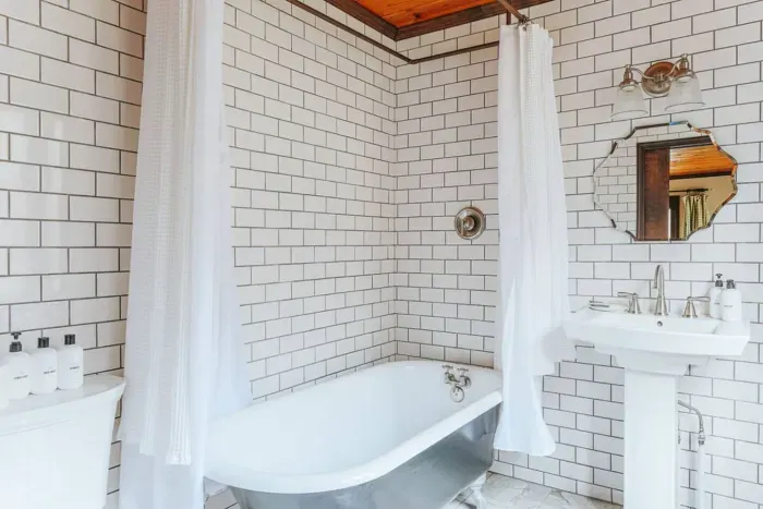 Bright bathroom with a soaking tub, subway tile walls, and a cozy wood-paneled ceiling.