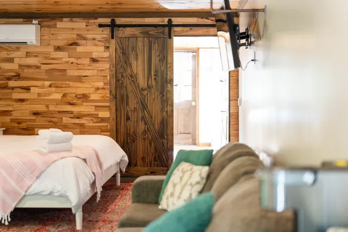 Cozy rustic studio with barn door, sofa, TV, and warm wood interiors