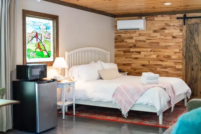 Cozy rustic bedroom with queen bed, mini fridge, microwave, and AC
