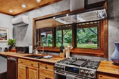 Fully equipped Garden Suite kitchen with a gas range, dishwasher, microwave, and sink overlooking the greenery.