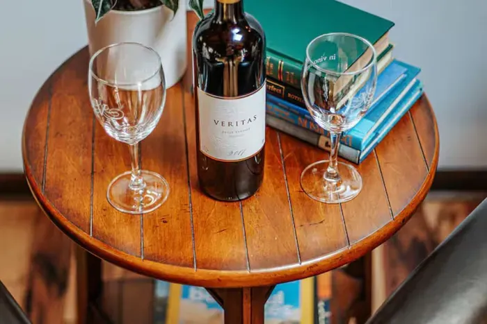 Cozy sitting area with a wine bottle, elegant glasses, books, and a touch of greenery.