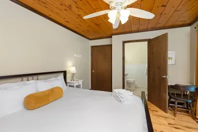 Bright, inviting bedroom with a comfortable bed, warm wood accents, and a private ensuite bathroom.