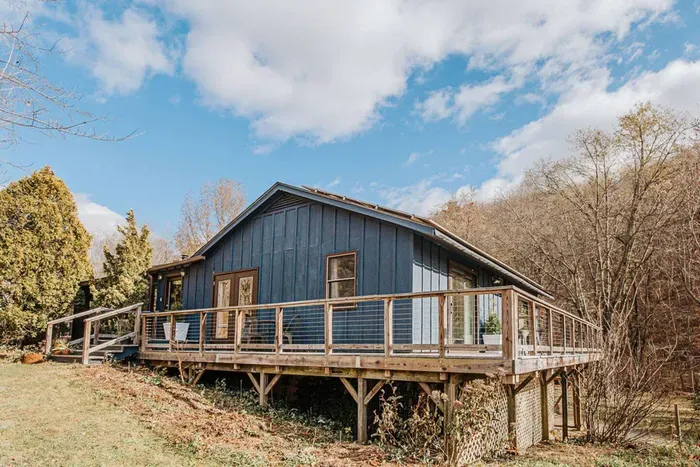 Spacious mountain retreat with a wraparound deck, surrounded by peaceful woodland scenery.