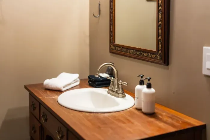Cozy bathroom vanity with a warm wood countertop, fresh towels, and elegant vintage accents.