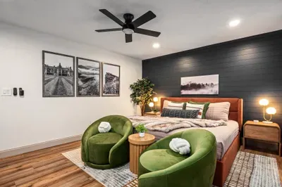 Modern king bedroom with cozy lounge chairs and bold accent wall