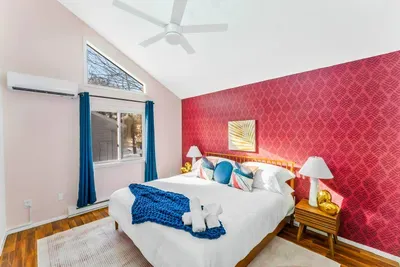 Sleep in style in this vibrant 2nd-floor bedroom featuring a plush king bed, vaulted ceilings, and bold design details.