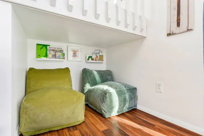 Discover a cozy reading nook tucked under the stairs, complete with plush seating and a selection of children's books.  Perfect for a quiet escape or storytime with the little ones.