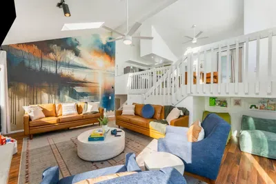 Gather in the bright and spacious living area with soaring ceilings. an inspiring lake-themed mural, and ample cozy seating.  Perfect for family time, conversation, and relaxation in style.
