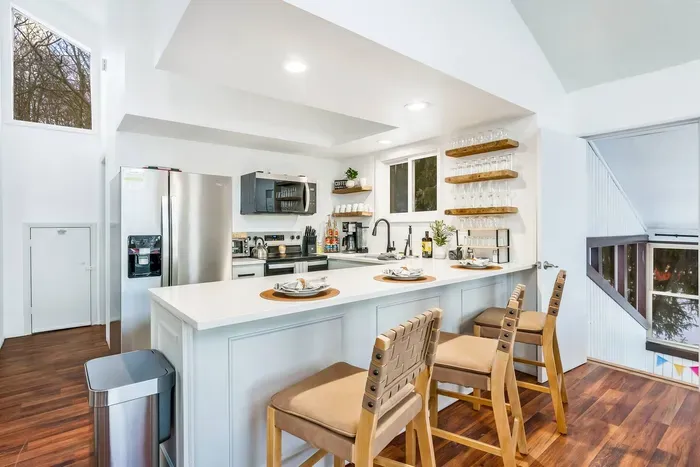 Enjoy the fully equipped, modern kitchen with stainless steel appliances, open shelving, and a spacious breakfast bar. Perfect for preparing family meals overlooking the surrounding natural beauty.