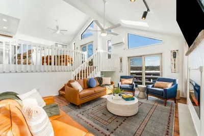 Enjoy abundant natural light and panoramic views in this open concept living space.  With vaulted ceilings, large windows, and easy access to the deck, it's perfect for relaxing or entertaining in a bright, inviting atmosphere!