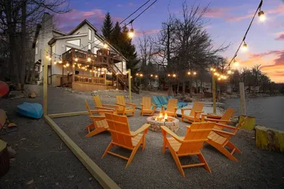 Golden hour at Water’s Edge Hideaway — a lakefront Poconos retreat where cozy Adirondack chairs, string lights, and firepit gatherings meet tranquil water views. Watch the sunset reflect off the lake as you unwind by the fire with a glass of wine.