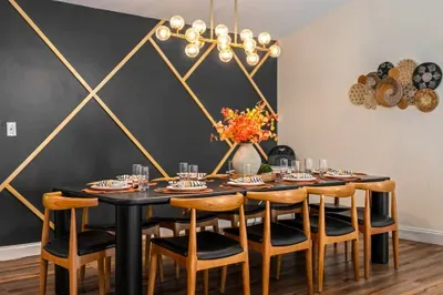 Elegant dining room for 8 with bold accent wall and modern chandelier