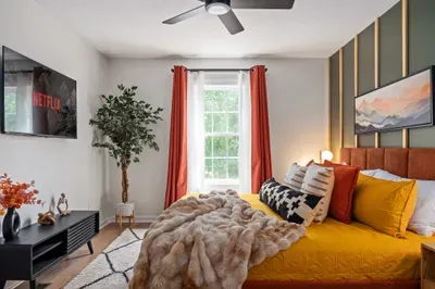 Cozy designer bedroom with TV, natural light, and bold modern accents