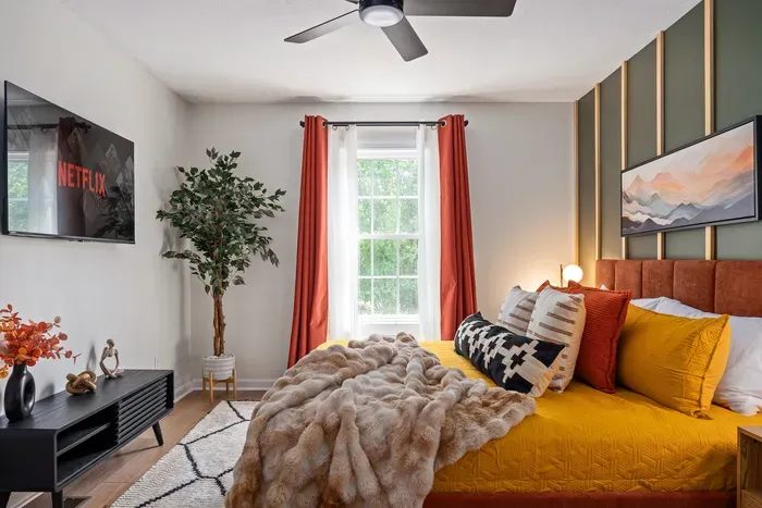 Cozy designer bedroom with TV, natural light, and bold modern accents