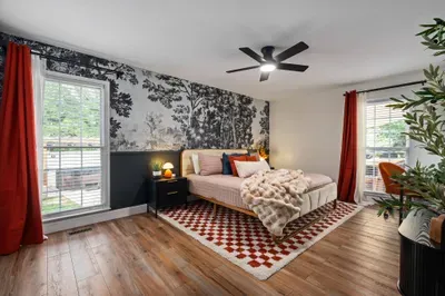Stylish, sunlit bedroom with mural wall, cozy bed, and workspace