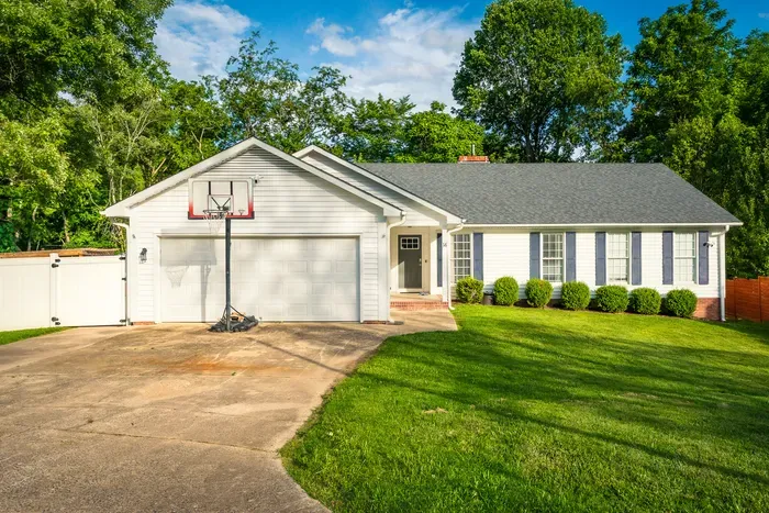 Charming home with spacious driveway, garage, and lush green yard