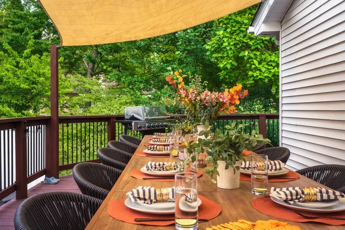 Spacious shaded deck with alfresco dining, grill, and lush green views