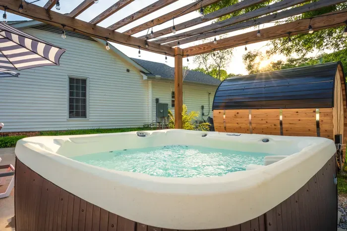 Private hot tub under pergola lights with sauna for a spa-like escape