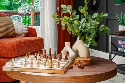 Cozy designer living room with chess table, greenery, and balcony light